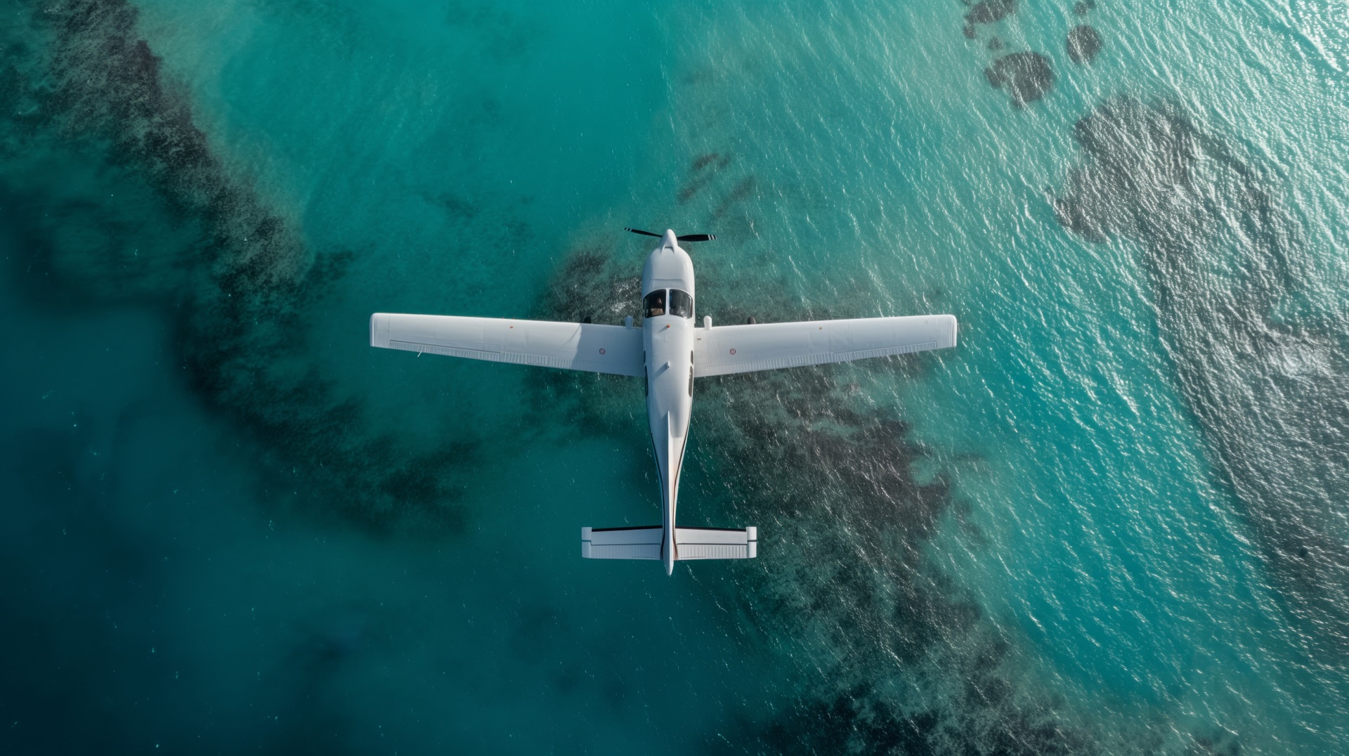 Top-down view of an aircraft over turquoise water and reefs
