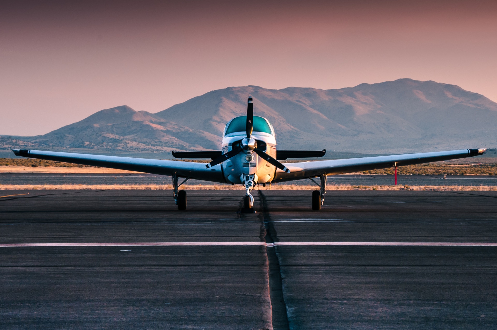 Owner's piston single head-on on the runway at dusk, mountains behind
