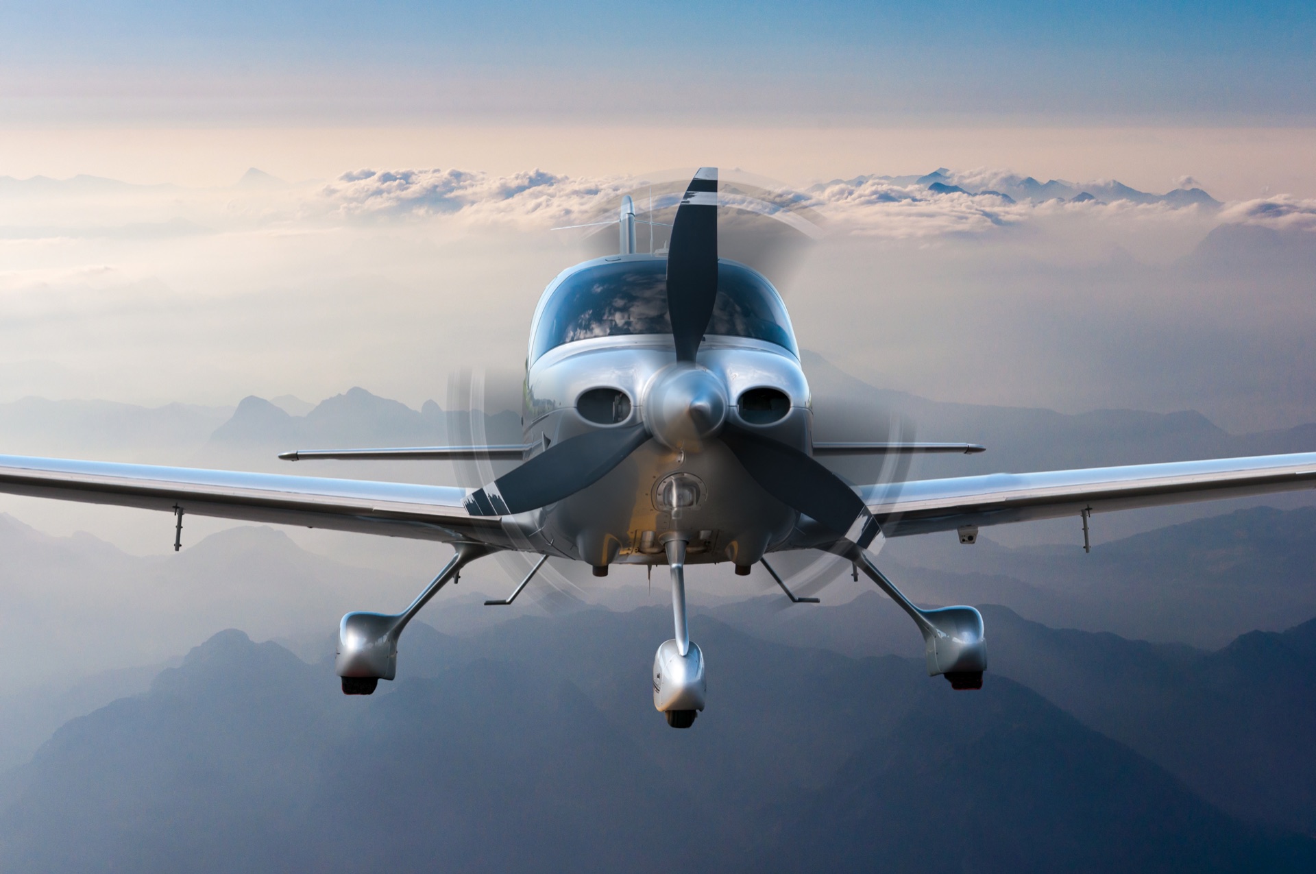 Piston single head-on in flight above hazy mountain ridges